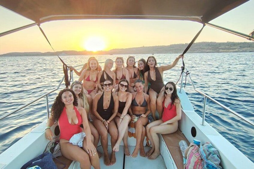 A group of people on a boat with a sunset in the background. 5