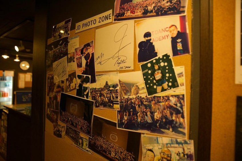 A wall covered with various photographs and posters, including a 'JD PHOTO ZONE' sign. 2
