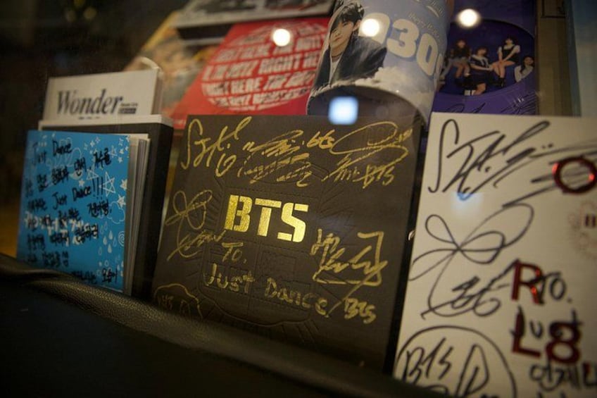 A shelf with various items including a BTS album, a Wonder magazine, and other merchandise. 1