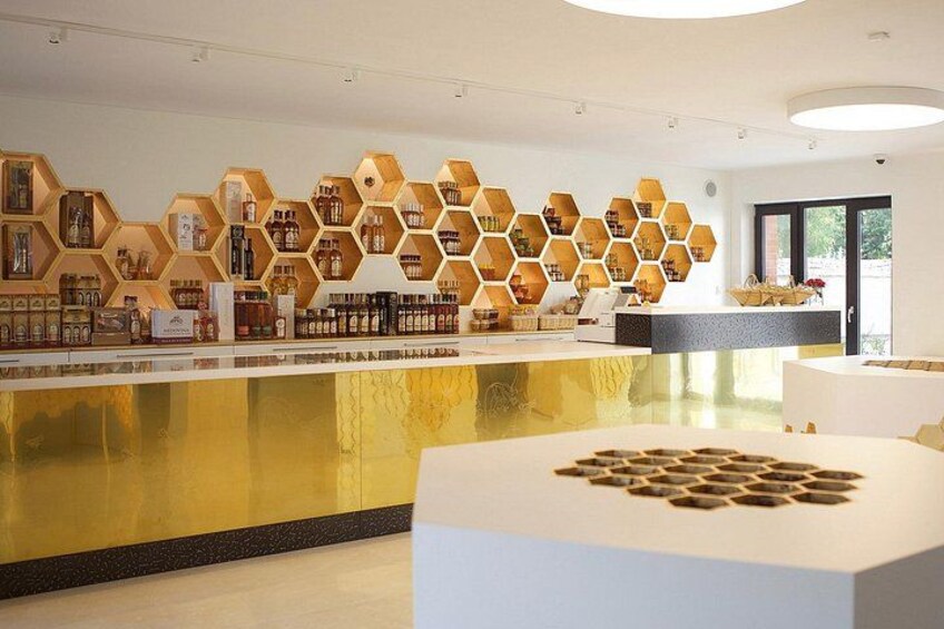 A modern bar with hexagonal shelves displaying bottles, a reflective gold counter, and a white seating area. 2
