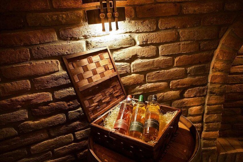 A wooden chest filled with bottles, placed against a brick wall with a lit switchboard above it. 4