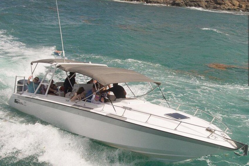 Een speedboot met passagiers vaart door turquoise water. 4