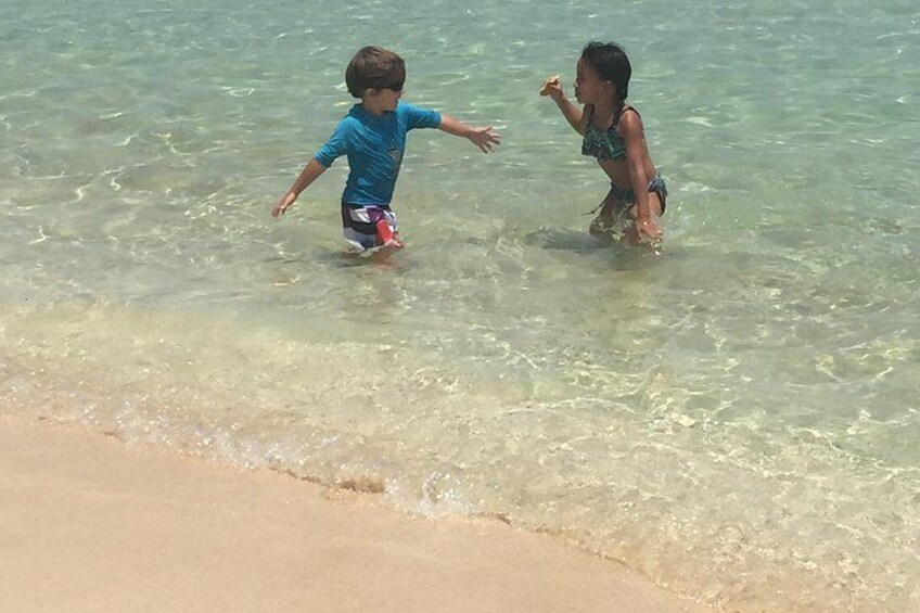 Twee kinderen die in ondiep water aan het spelen zijn op het strand. 3