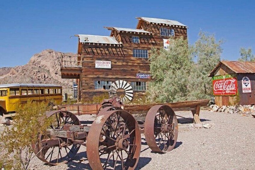 A wooden building with a sign for Red Crown Gasoline, a Coca-Cola sign, and a vintage trolley. 3