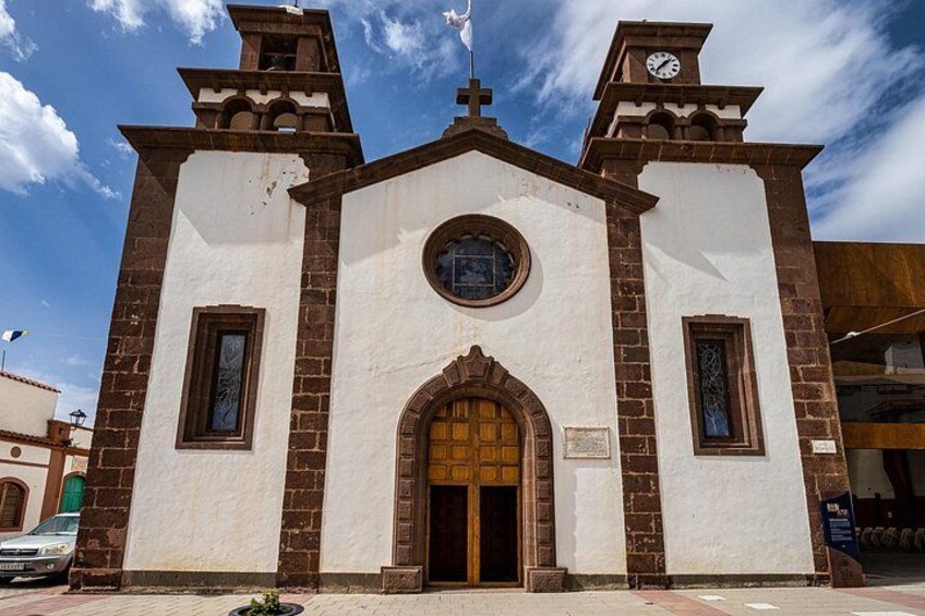 A church with a clock tower, arched entrance, and two side windows. 2