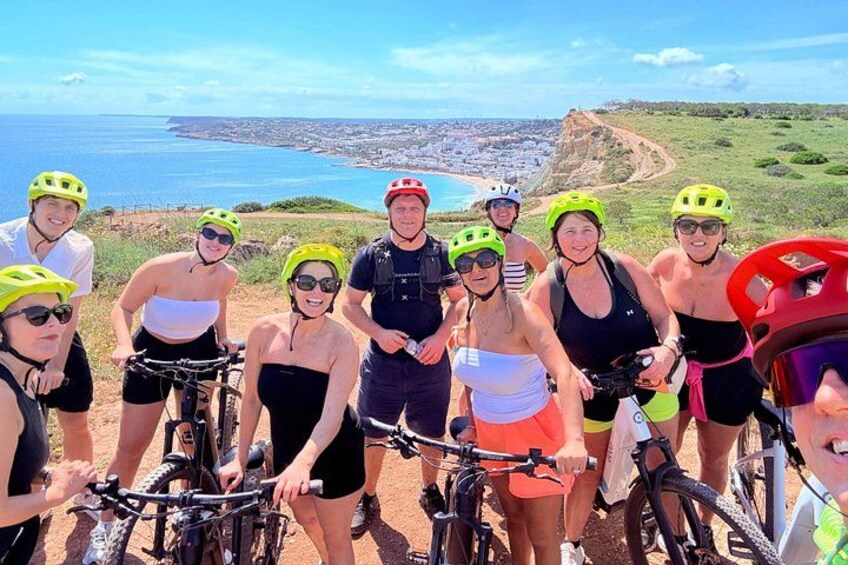 A group of cyclists on a coastal trail with a view of the ocean and cliffs. 1
