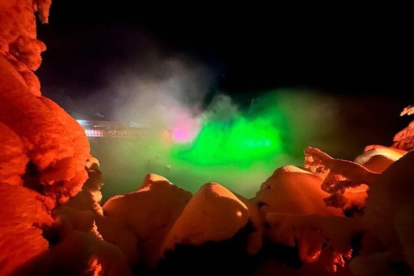 Schneebedeckte Felsen mit roten und grünen Lichtern im Hintergrund. 2