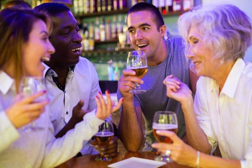 Un gruppo di persone sedute al bancone di un bar, con dei drink in mano. 4