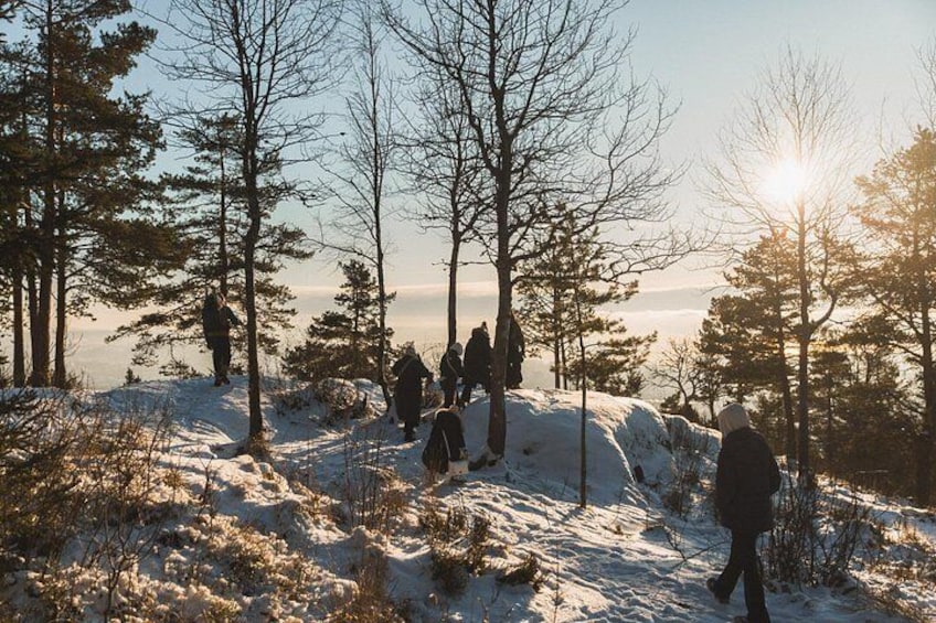 A group of people hiking in a snowy forest with trees and a clear sky. 5
