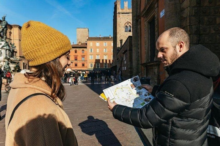 Deux personnes examinent une carte sur une place publique, avec des bâtiments historiques en arrière-plan. 3