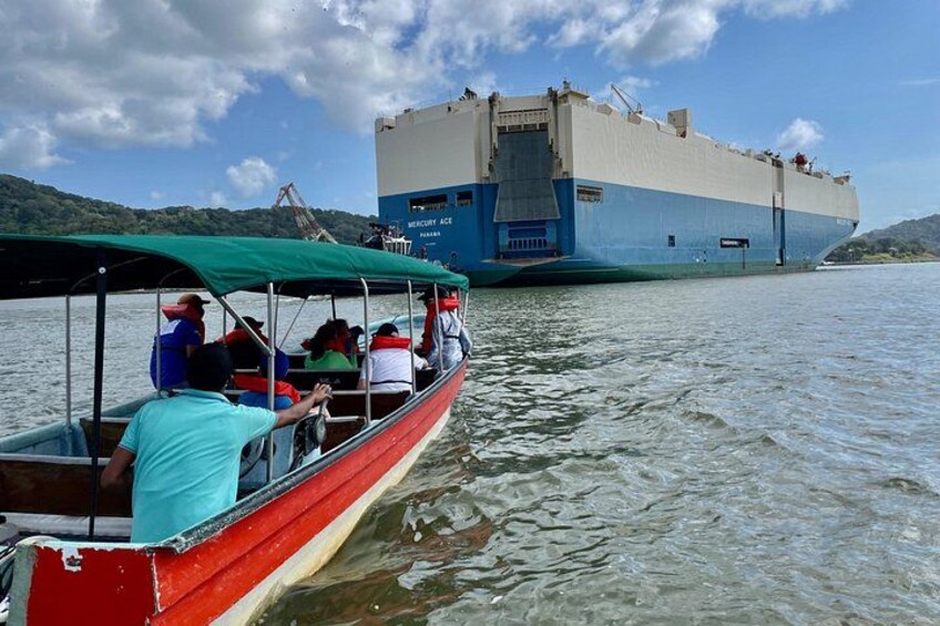 Un bote rojo con pasajeros, un barco azul y blanco al fondo, y un paisaje montañoso. 4