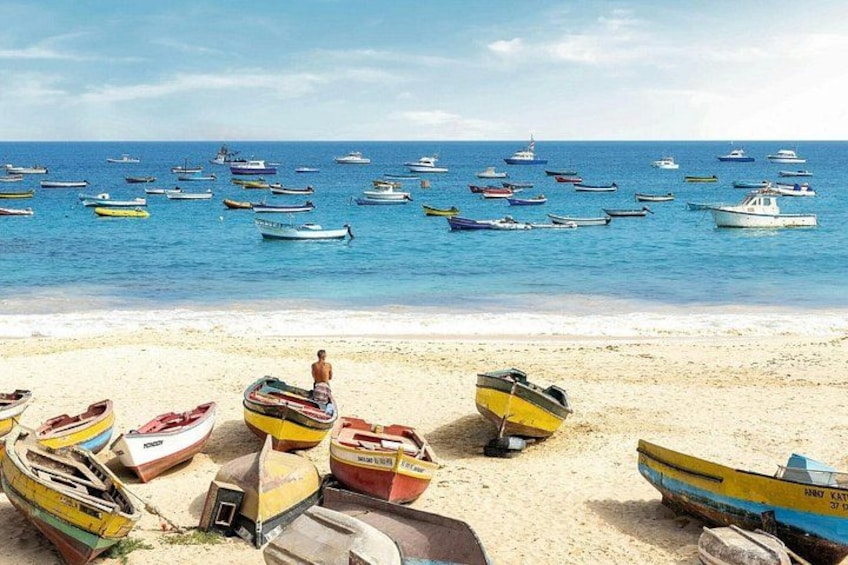 A beach with numerous small boats and a person sitting on a boat. 1