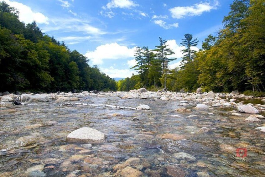 Un río con aguas cristalinas, rodeado de rocas y árboles. 4