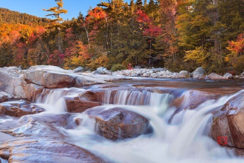 Una cascada con follaje otoñal al fondo. 3