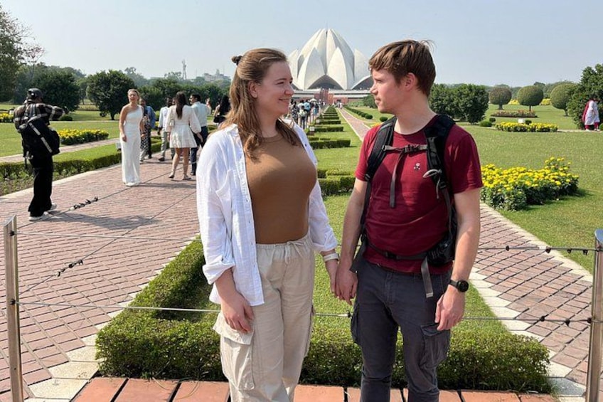 Dos personas de pie en un jardín con una edificación geométrica al fondo. 5
