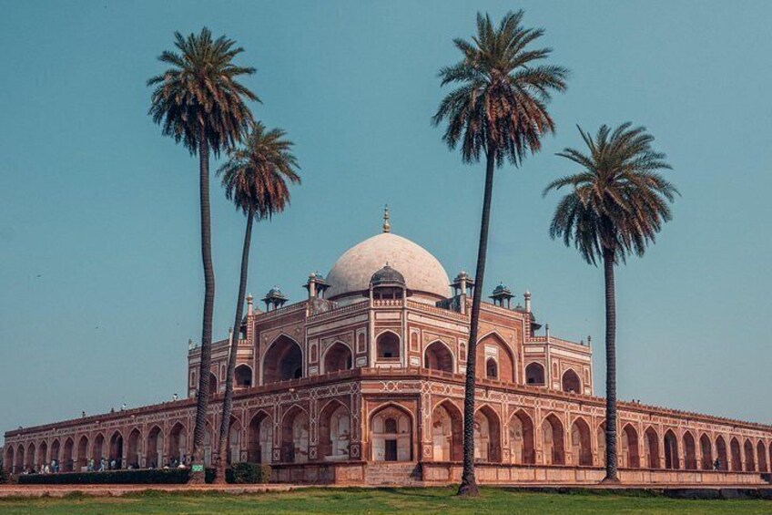 A large, historic building with a central dome and arched windows, surrounded by palm trees. 3