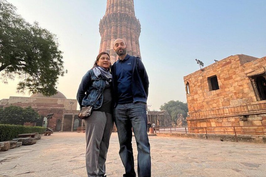 Un edificio histórico con un alto minarete, un área pavimentada y un árbol. 2