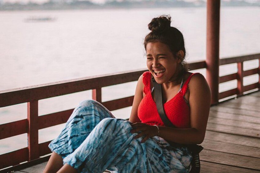 A person sitting on a wooden deck by a body of water. 3