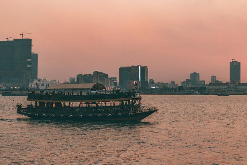 A riverboat with passengers, a city skyline in the background, and a sunset sky. 1