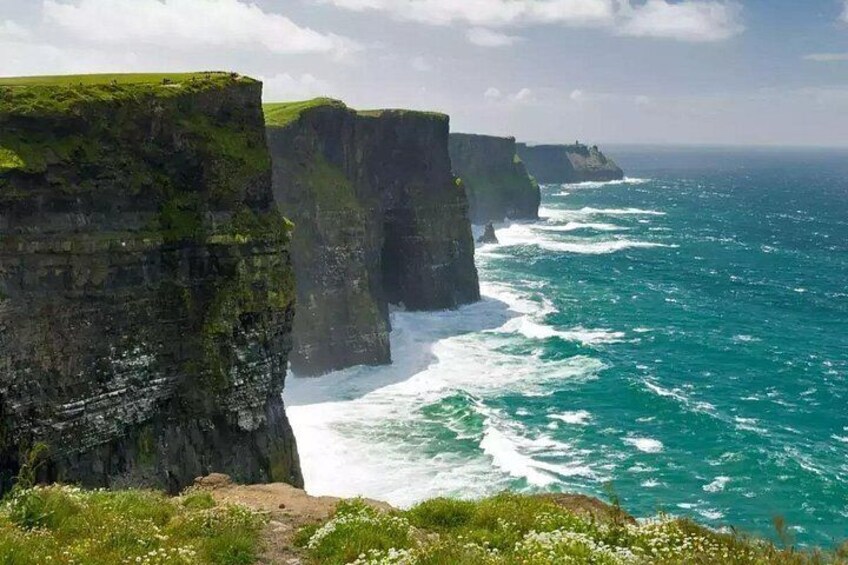 A coastal cliff with a grassy top and a rugged coastline. 3