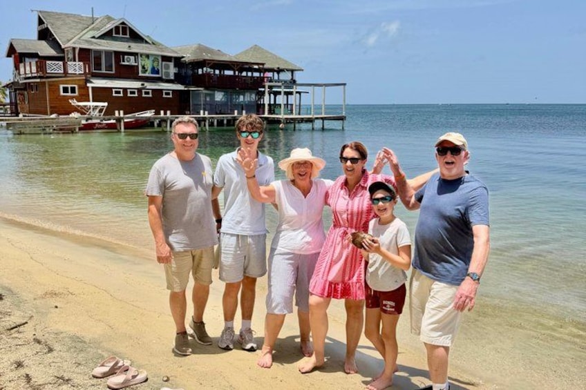A group of people on a beach with a house and dock in the background. 4
