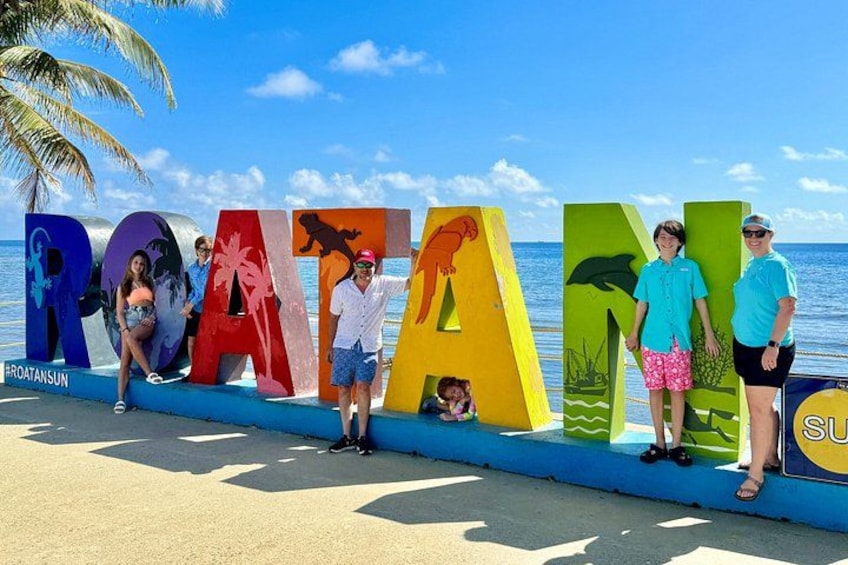 A beach with colorful letters spelling 'ROAMING' and palm trees in the background. 1