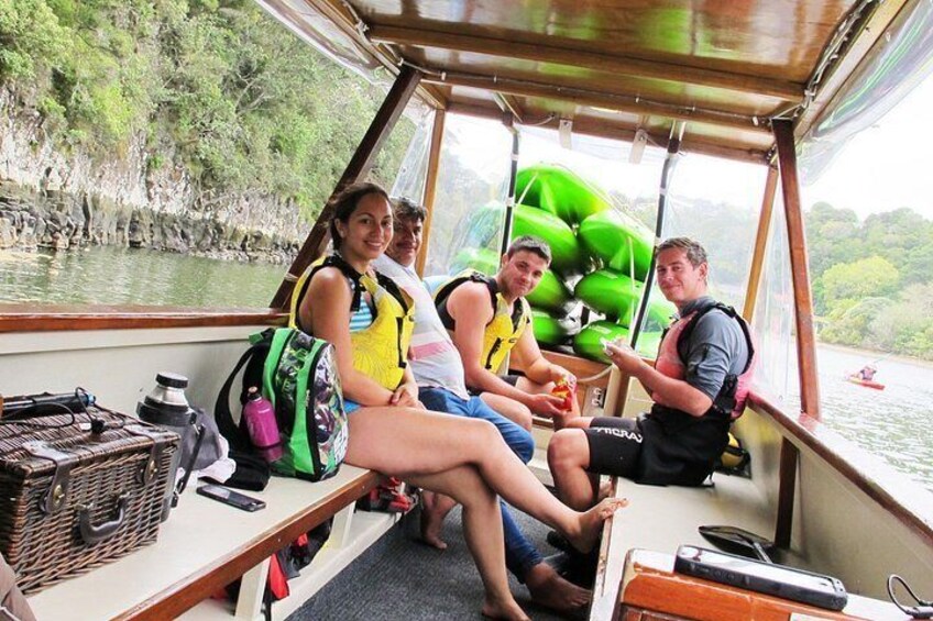 A boat with passengers wearing life jackets, a green kayak, and a basket on the deck. 4