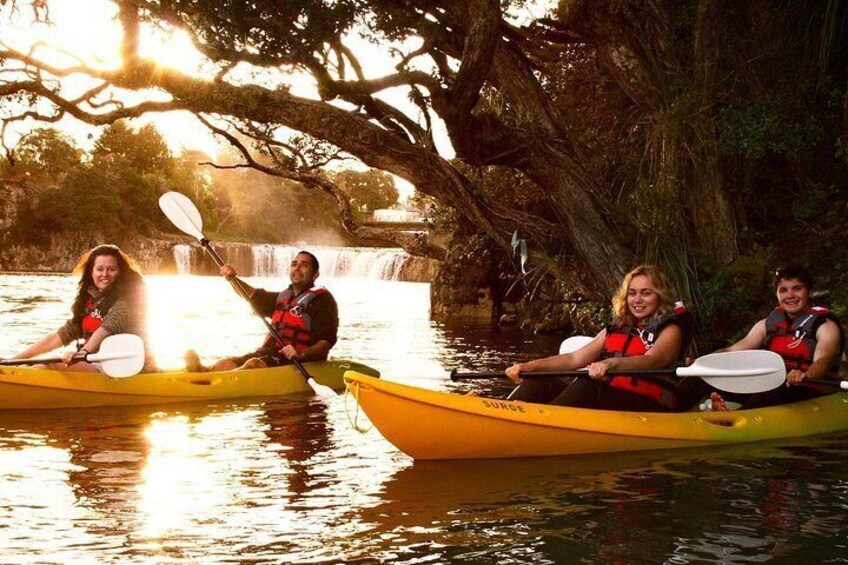 Three people kayaking on a calm river with a waterfall in the background. 5