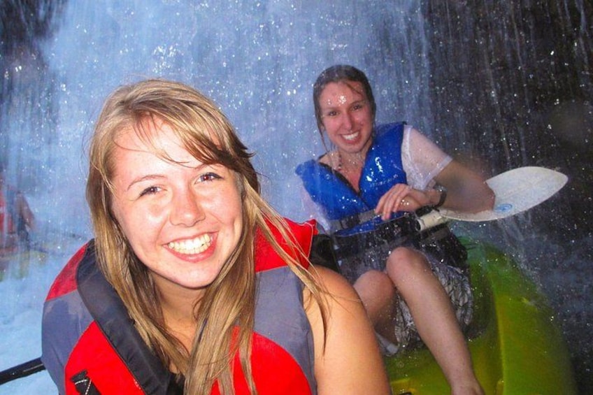 Eine Person trägt eine rote Rettungsweste auf einer Wasserattraktion, umgeben von spritzendem Wasser. 2