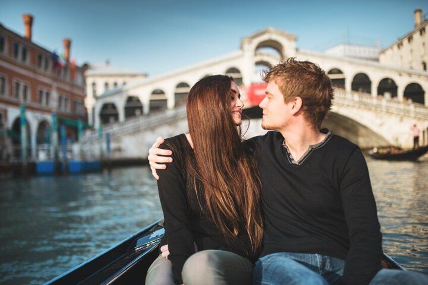 Un couple se trouve sur un bateau dans un canal, avec des bâtiments historiques et un pont en arrière-plan. 2