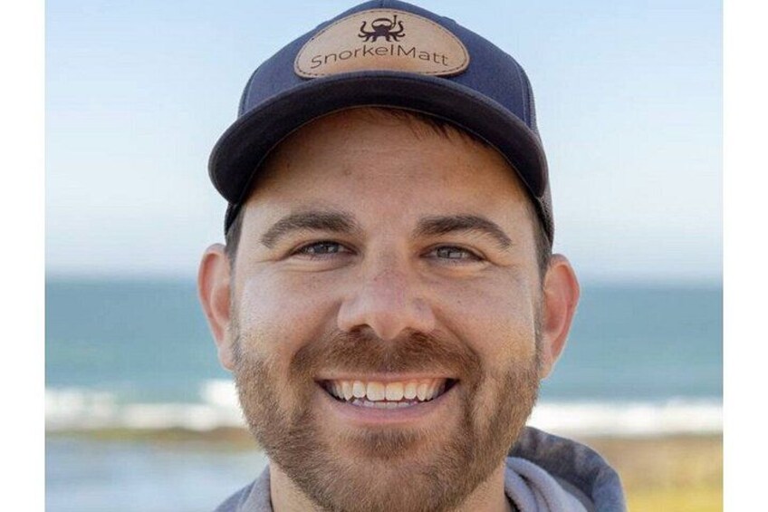 A person wearing a cap with a logo, standing near a body of water. 2