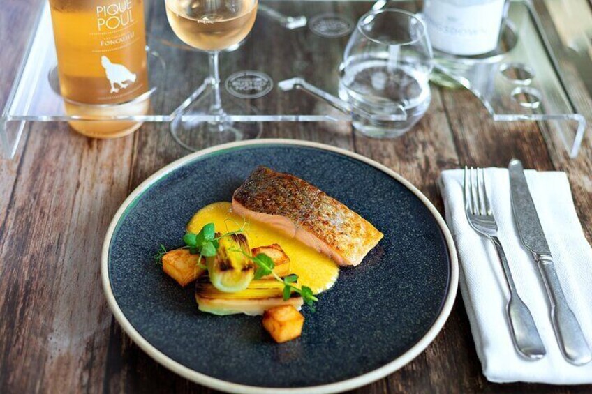 A plate of food with a piece of fish and vegetables on a dark plate. 1