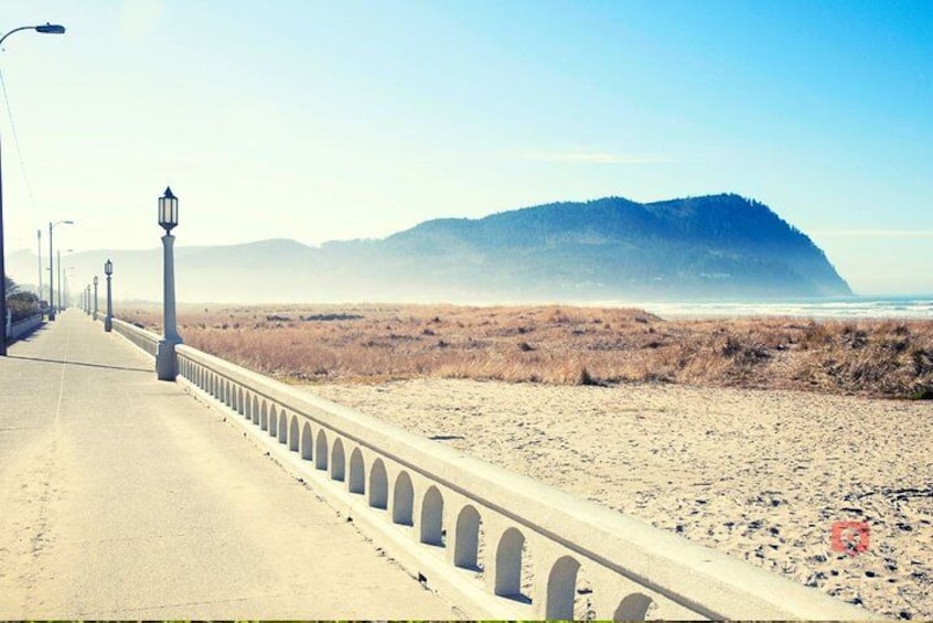 A coastal road with street lamps, a sandy beach, and a mountain in the background. 2