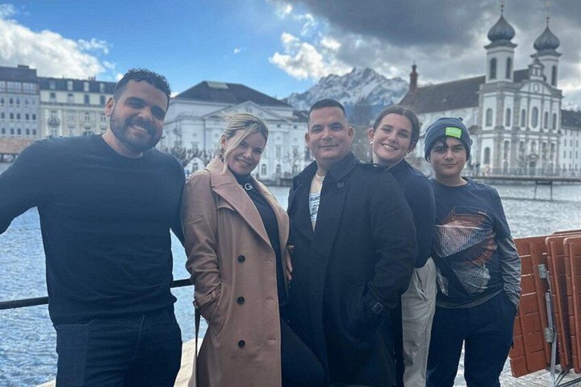 Un grupo de personas en un barco, con un paisaje urbano y montañas al fondo. 3