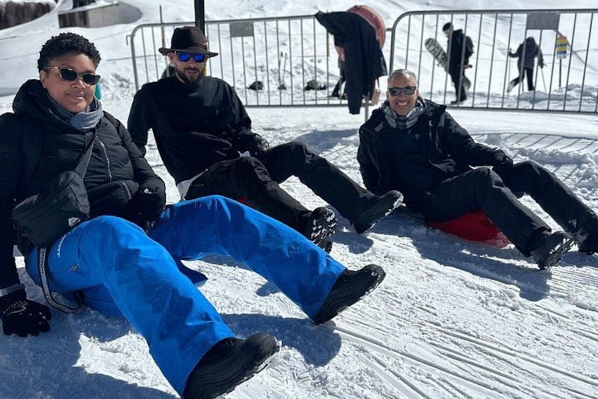Personas sentadas sobre suelo cubierto de nieve con tablas de snowboard. 4