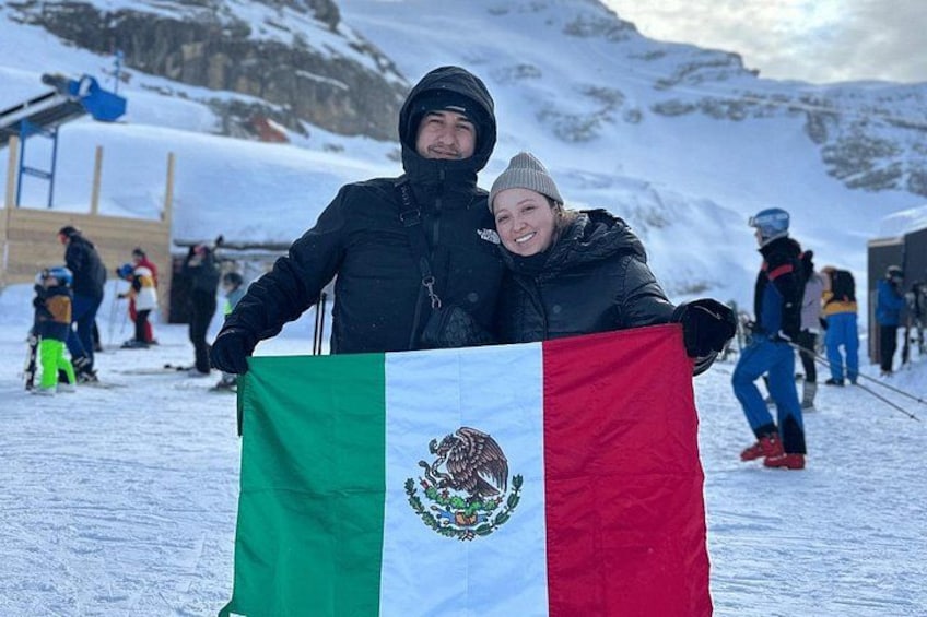 Una persona sostiene una bandera con un campo verde, blanco y rojo y un escudo de armas. 2