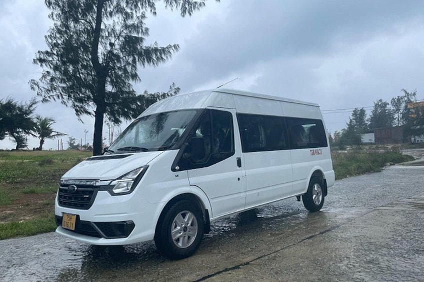 A white van parked on a wet road with puddles. 2