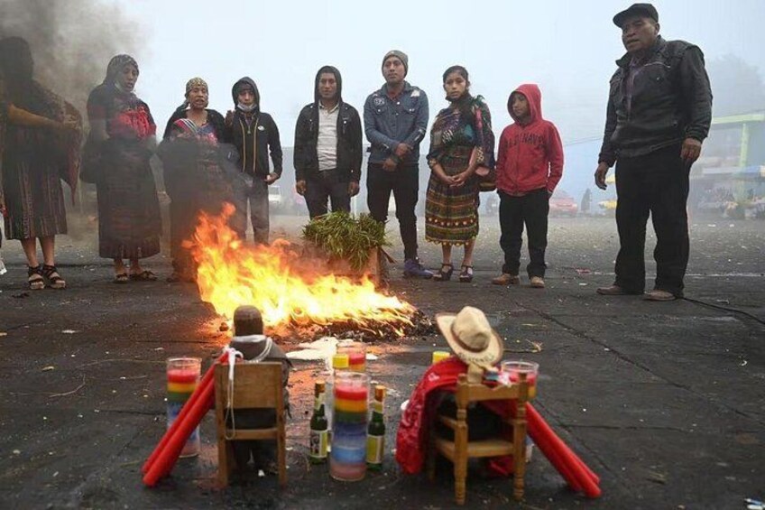 A group of people gathered around a fire with various items on the ground. 3