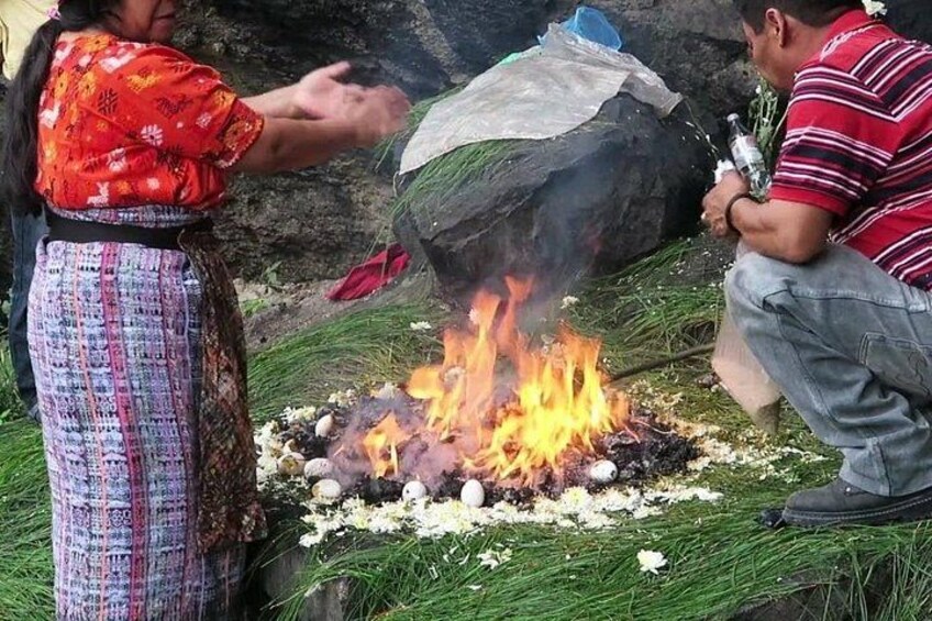A person in traditional attire tending to a fire with burning wood and flowers. 4