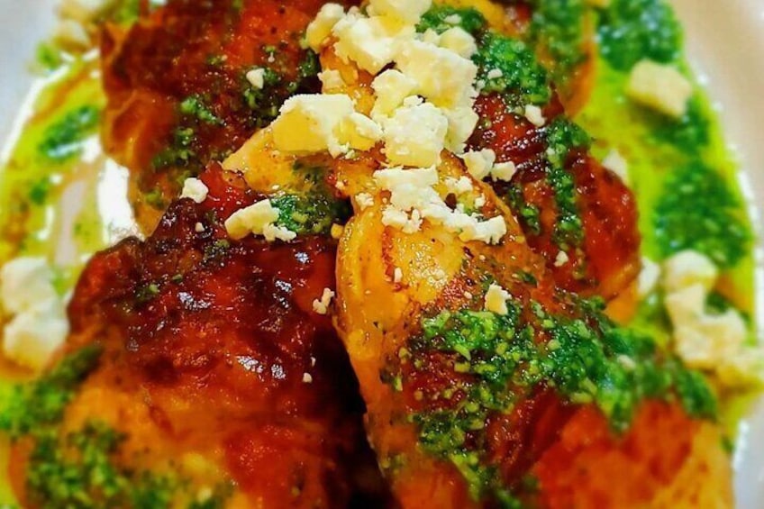 A dish with meat, green sauce, and crumbled cheese. 1