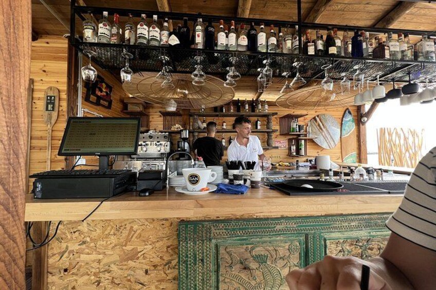 Un bar con paredes de madera, una barra con una computadora y estantes con botellas y vasos. 3