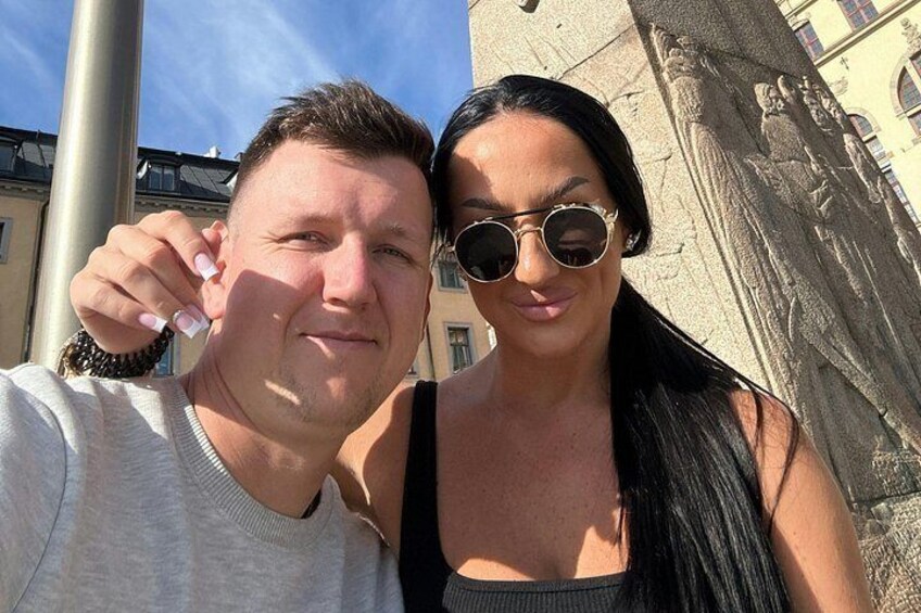 Two people taking a selfie with a building and a sculpture in the background. 5