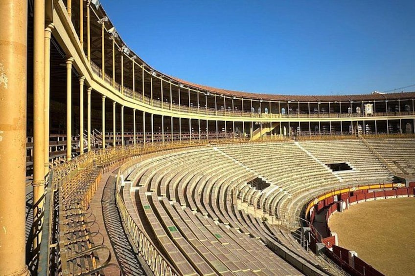Un grand stade vide, doté de gradins et d’une scène centrale. 3