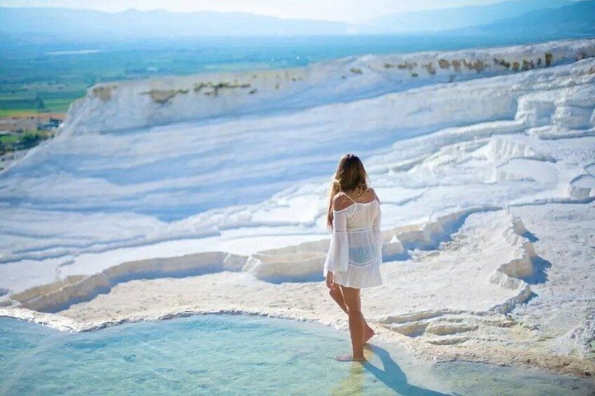 A person standing on a terraced landscape with clear water at the base. 5