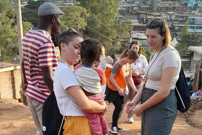 A group of people standing on a dirt path with a hilly urban background. 3