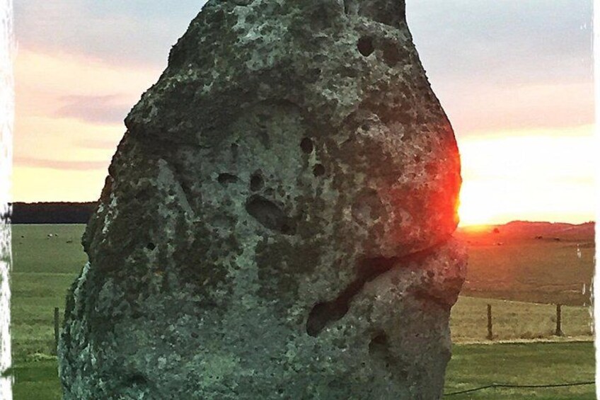 A large rock formation with holes, set against a sunset sky. 3