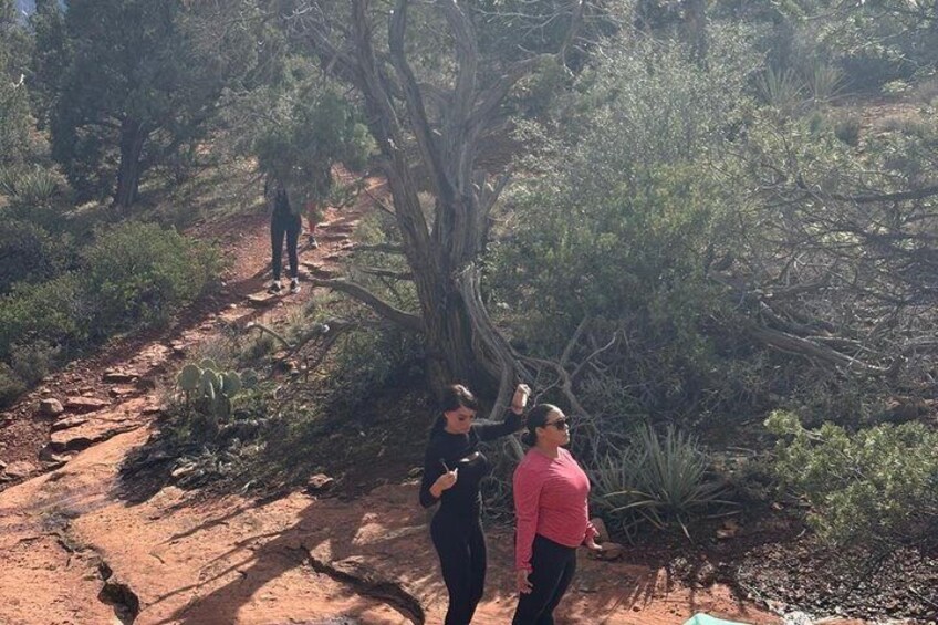 A dirt trail in a dry, wooded area with sparse vegetation and a large tree in the foreground. 5