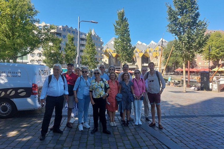 A group of people standing on a cobblestone street with buildings and trees in the background. 3