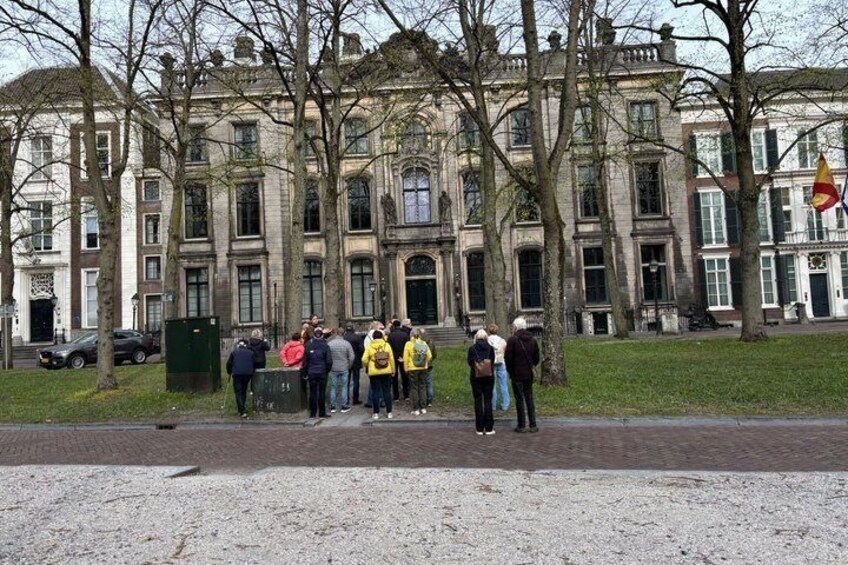 A group of people standing in front of a historic building with a flag. 4