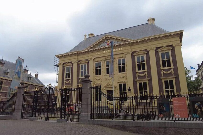 A historic building with a classical facade, a prominent entrance gate, and a flagpole. 5